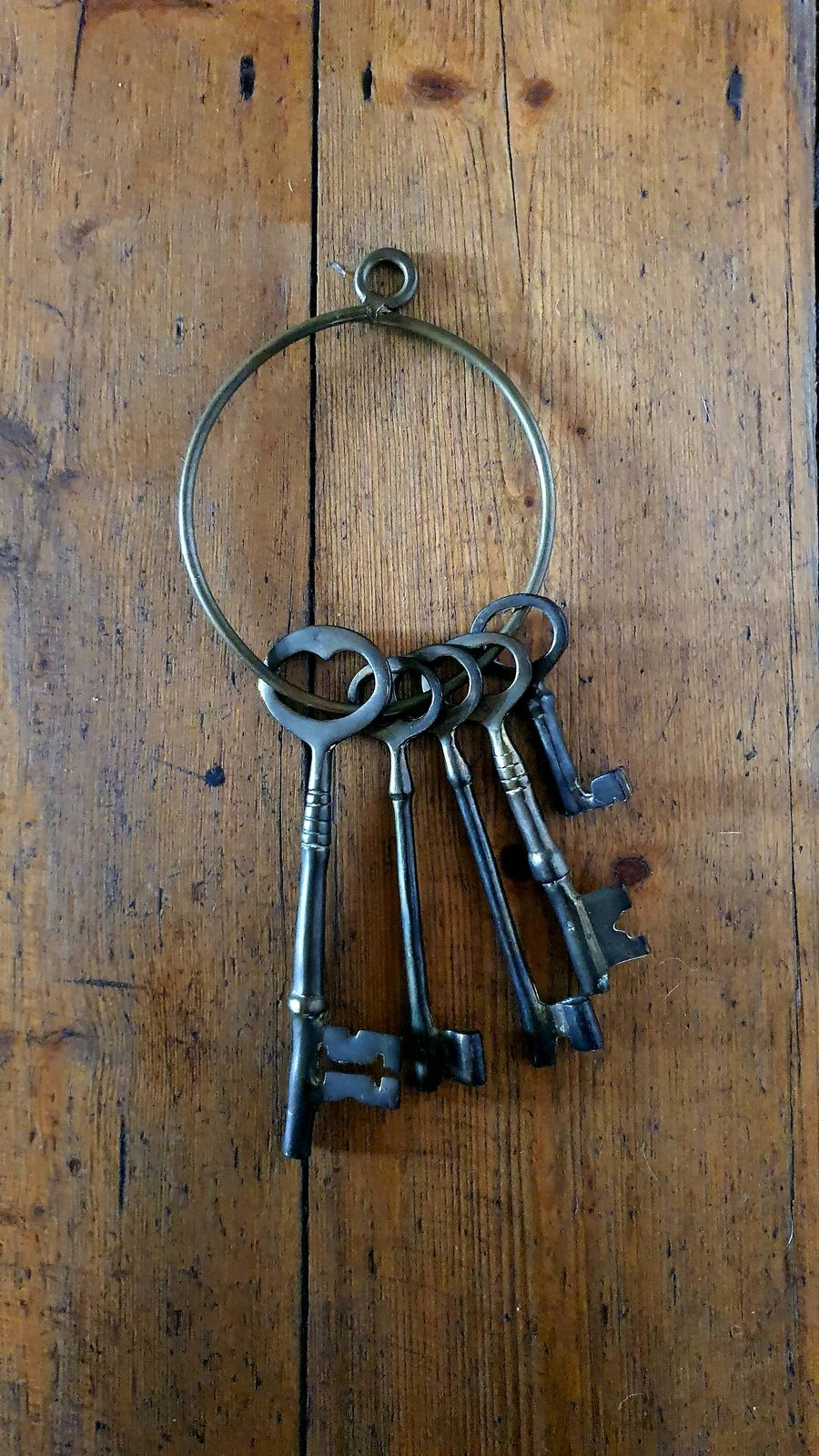 Antique brass keys hanging from a ring on aged wood